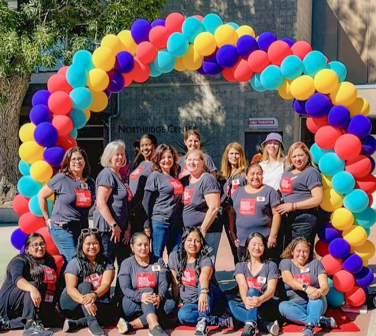 The smiling Family Focus staff poses beneath an archway of balloons