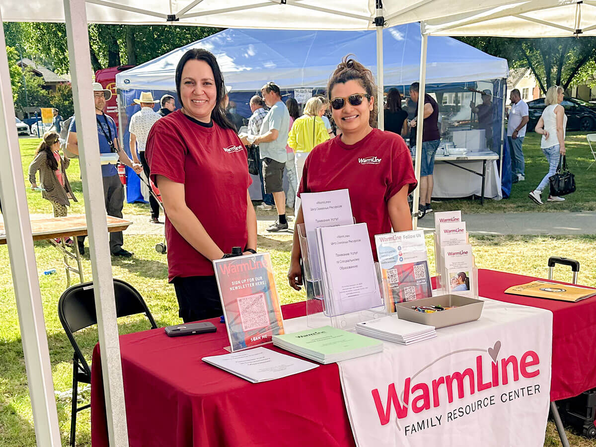 WarmLine staff man a table at an outdoor event.