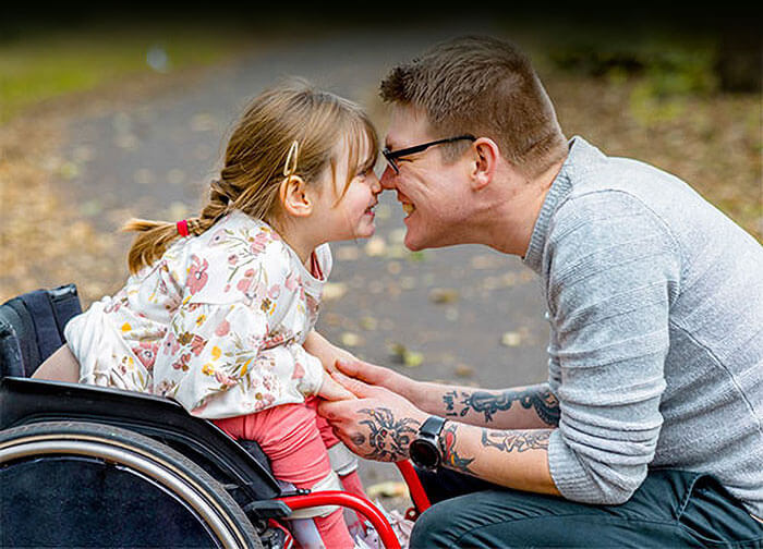 A girl in a wheelchair gives her father an Eskimo kiss