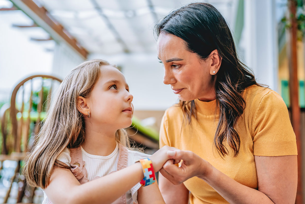 A mother holds hands with her daughter with autism